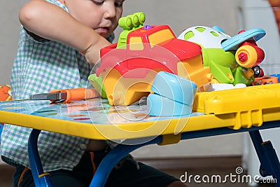 A child with toy pliers and drill repairs cars Stock Photo