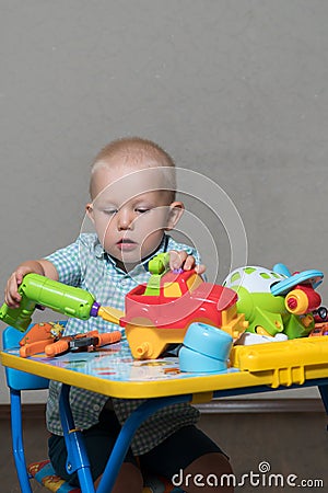 A child with toy pliers and drill repairs cars Stock Photo