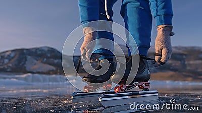 The child train on ice speed skating. Athlete puts on skates. The girl skates in the winter in sportswear, sport glasses Stock Photo