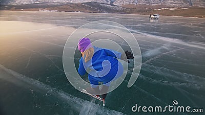 The child train on ice speed skating. The athlete at the start, in a sports stance. The kid girl skates in the winter in Stock Photo