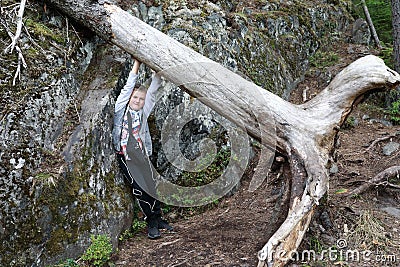 Child trying to lift tree trunk in forest Stock Photo