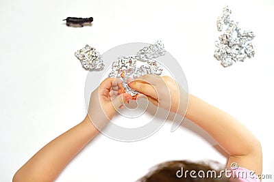 The child unfolds the foil surprise and finds an animal figurine there. the concept of early development according to the Stock Photo