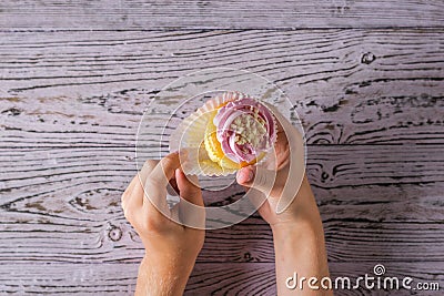 The child unfolds a freshly prepared cupcake on a wooden table. Stock Photo