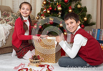 Child unpack gift boxes near christmas tree, decoration at home, happy emotion, winter holiday concept Stock Photo