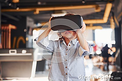 Child in virtual reality eyewear and in casual clothes have fun in playroom Stock Photo