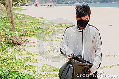 Child volunteer collecting garbage on beautiful beach at Karon Beach Stock Photo