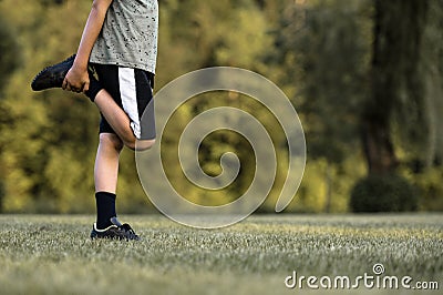 Child warming up before soccer practice stretching his leg Stock Photo