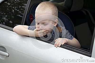 The child was rocked in a car seat. The boy suffers from kinetosis and motion sickness. The concept of motion sickness and Stock Photo