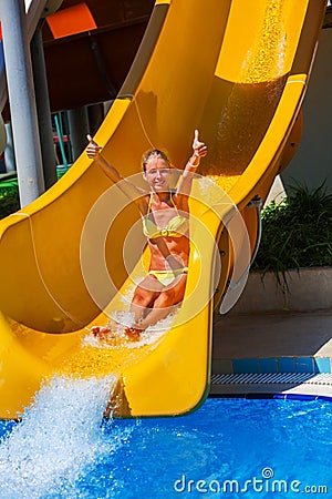 Child on water slide at aquapark show thumb up. Stock Photo