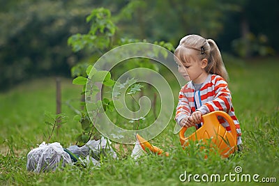 Child with orange water can outside watering just planted tree Stock Photo