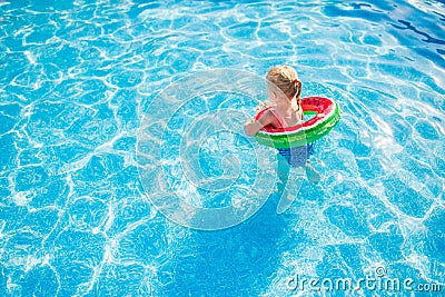 Child with watermelon inflatable ring in swimming pool. Little girl learning to swim in outdoor pool. Water toys and floats for Stock Photo