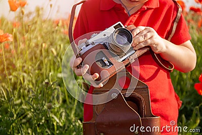 Child wathing in camera on the field with wild poppies. Stock Photo