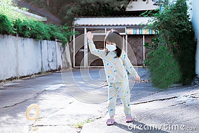 Child wear masks to prevent PM2.5 dust while playing outside. Children play with a round ring to practice directional control. Stock Photo
