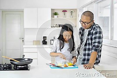 Child whisking eggs while cooking with her father Stock Photo