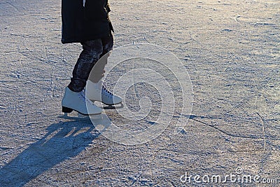 A child in white skates clumsily rides in winter on the ice of a river or lake Stock Photo