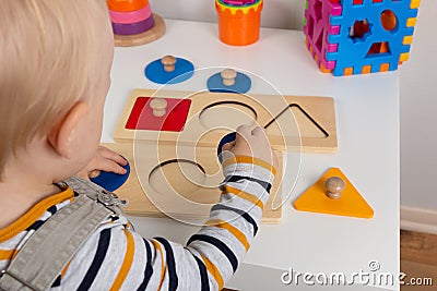 Child works with Montessori material for fine motor skills, sensory play. Playing children with geometry figures Stock Photo