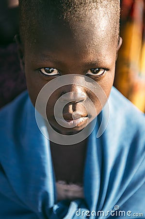 BOYA TRIBE, SOUTH SUDAN - MARCH 10, 2020: Child wrapped in blue cloth looking at camera while living in Boya Tribe village in Editorial Stock Photo