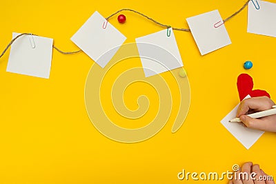 Child writes a note on a sheet of paper on the clothesline. Bright background Stock Photo