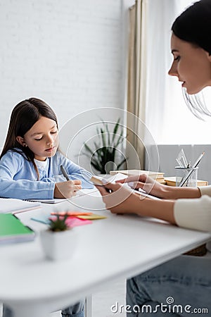 child writing dictation near nanny reading Stock Photo