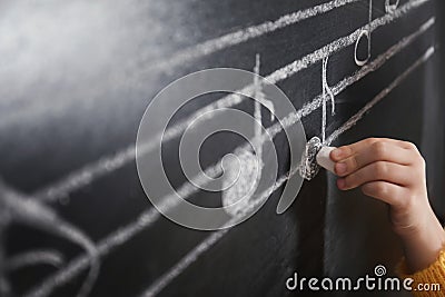 Child writing music notes on blackboard Stock Photo