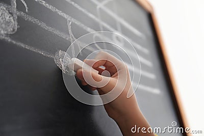 Child writing music notes on blackboard Stock Photo