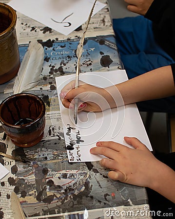 Child writing with a quill Editorial Stock Photo