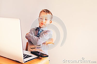 Child 5 years old working on a laptop with an angry face when business failing, humor image Stock Photo