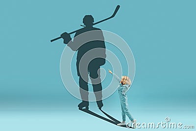 Childhood and dream about big and famous future. Conceptual image with boy and shadow of fit male hockey player on blue Stock Photo