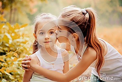 Childhood, family, friendship and people concept - two happy kids sisters hugging outdoors. Stock Photo