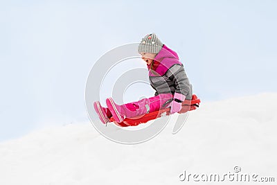 Happy little girl sliding down on sled in winter Stock Photo