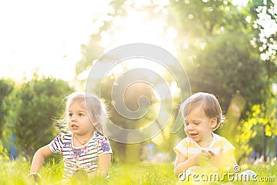 Childhood, summer and leisure concept - two cute happy little babies of irish twins boy and girl sitting in bright grass Stock Photo