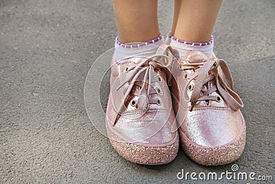 Childly legs in light pink color sneakers with glamor glitter and shoelaces Stock Photo