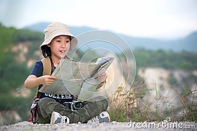 Children asian girl holding maps and travel backpacks standing in the mountain. Stock Photo