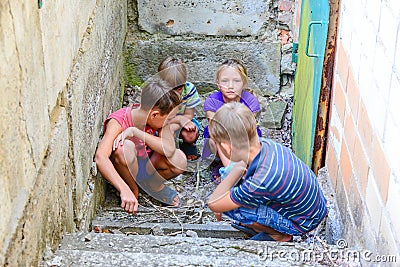 Children in the basement, three boys and a girl near the iron door are hiding on the steps from the outside world. Post-production Stock Photo