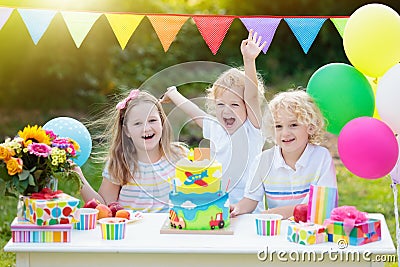 Children blow candles on birthday cake. Kids party Stock Photo