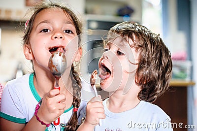 Children brother and sister eat chocolate from spoon Stock Photo