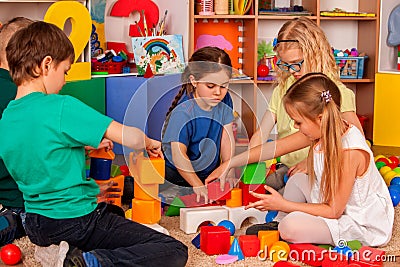 Children building blocks in kindergarten. Group kids playing toy floor . Stock Photo