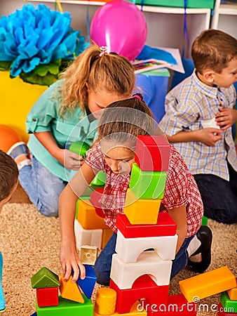 Children building blocks in kindergarten. Group kids playing toy floor . Stock Photo
