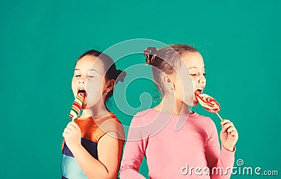 Children with busy faces pose with candies on green background Stock Photo