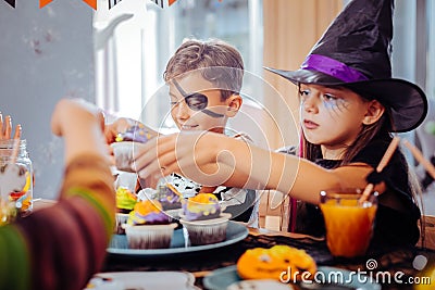 Children celebrating Halloween at kindergarten eating thematic sweets Stock Photo