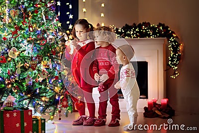 Children at Christmas tree. Kids at fireplace on Xmas eve Stock Photo