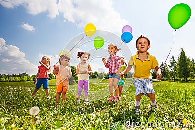 Children with colorful balloons running in field Stock Photo