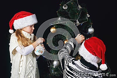 Children decorate the Christmas tree in the room. Stock Photo