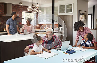 Children Doing Homework In Busy Multi Generation Family Home Stock Photo