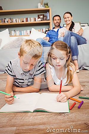 Children drawing on book while parents looking at them Stock Photo