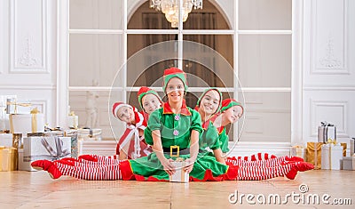 Children dressed in costumes of Christmas elves sitting in twine one after another in front of the mirror in the spacious white Stock Photo