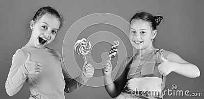 Children eat big colorful sweet caramels. Sisters with lollipops Stock Photo