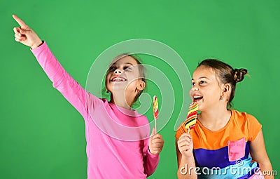 Children eat big colorful sweet caramels. Sisters with lollipops. Stock Photo