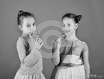 Children eat big colorful sweet caramels. Sisters with round, long shaped lollipops. Girls with happy faces Stock Photo
