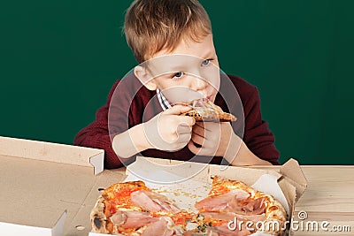 Children eat Italian pizza in the cafe. School boy is eating pizza for lunch. Child unhealthy meal concept. Hungry kids. Pizza re Stock Photo